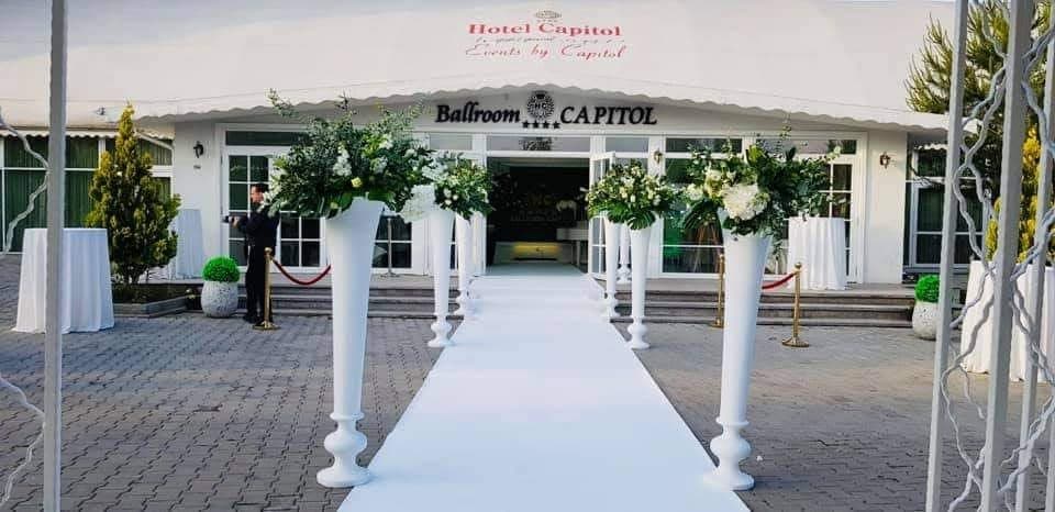 Events by Capitol (Iași): intrarea în ballroom cu covor alb și aranjamente florale