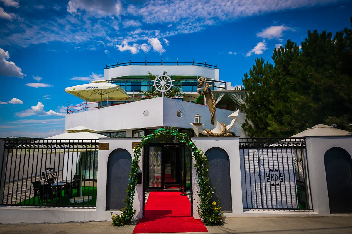 Restaurant Titanic (Valea Adâncă, Iași): intrarea în restaurant cu covor roșu și arcadă verde