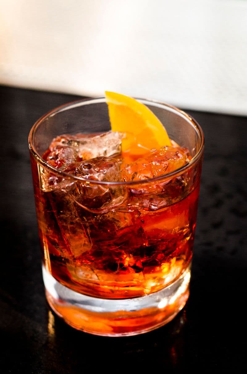 Cocktail cu gheață și felie de portocală într-un pahar scurt